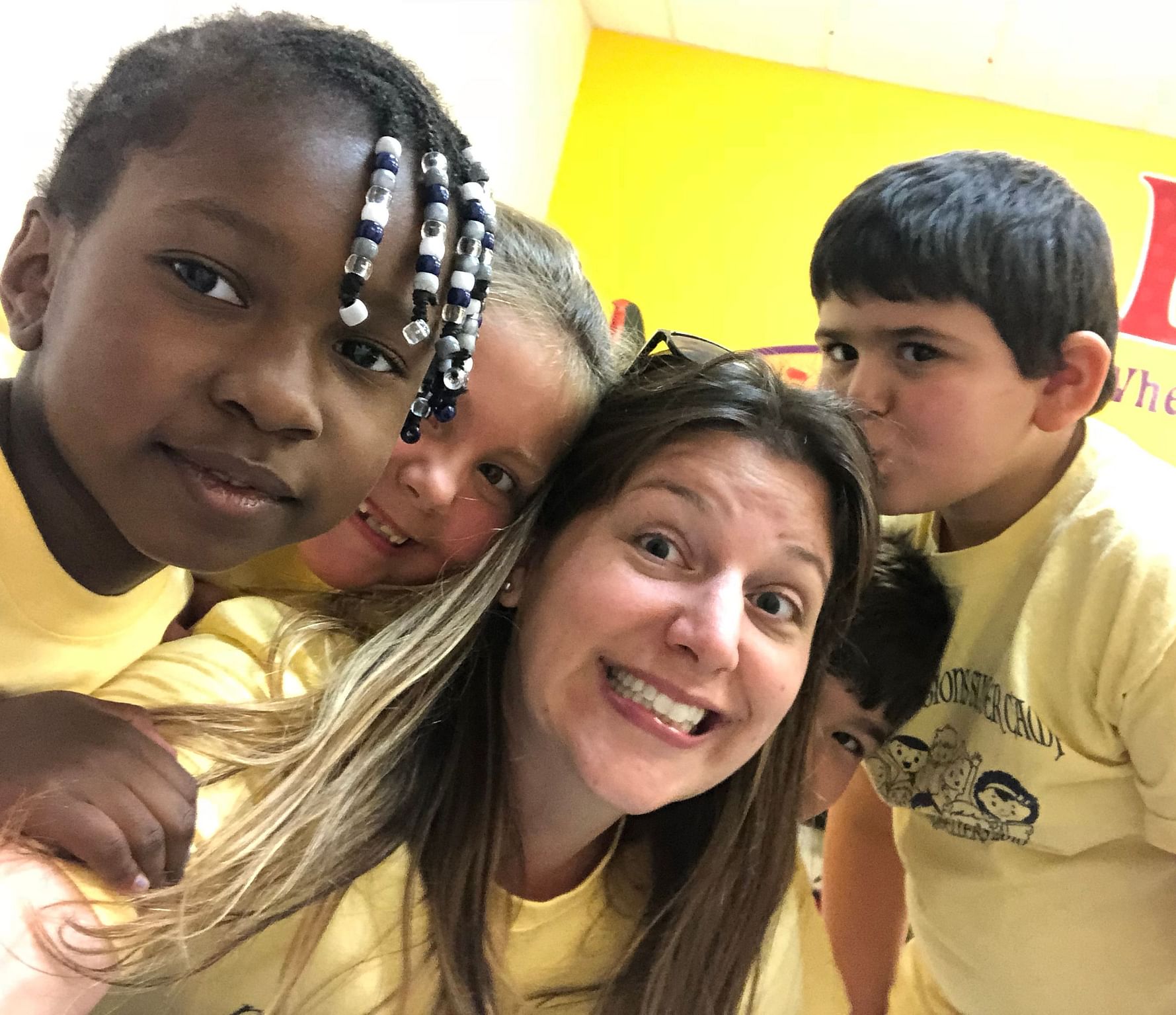 Tiffany Searles smiling while surrounded by young students in yellow shirts