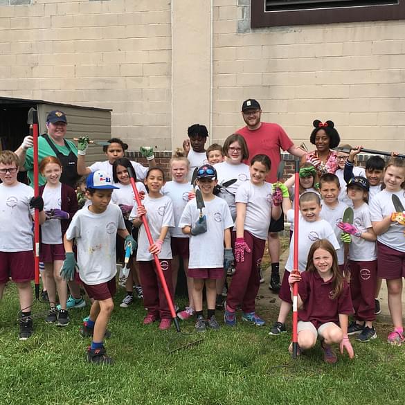 Group of young students outside with rakes