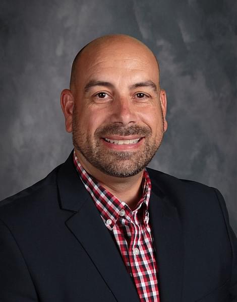 smiling white male with beard with plaid shirt and navy suitcoat