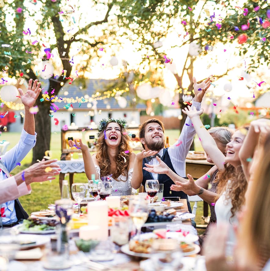 People laugh and throw confetti in the air at a wedding party