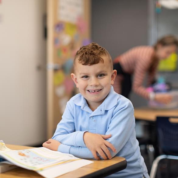  Young school girl smiling at desk in classroom 