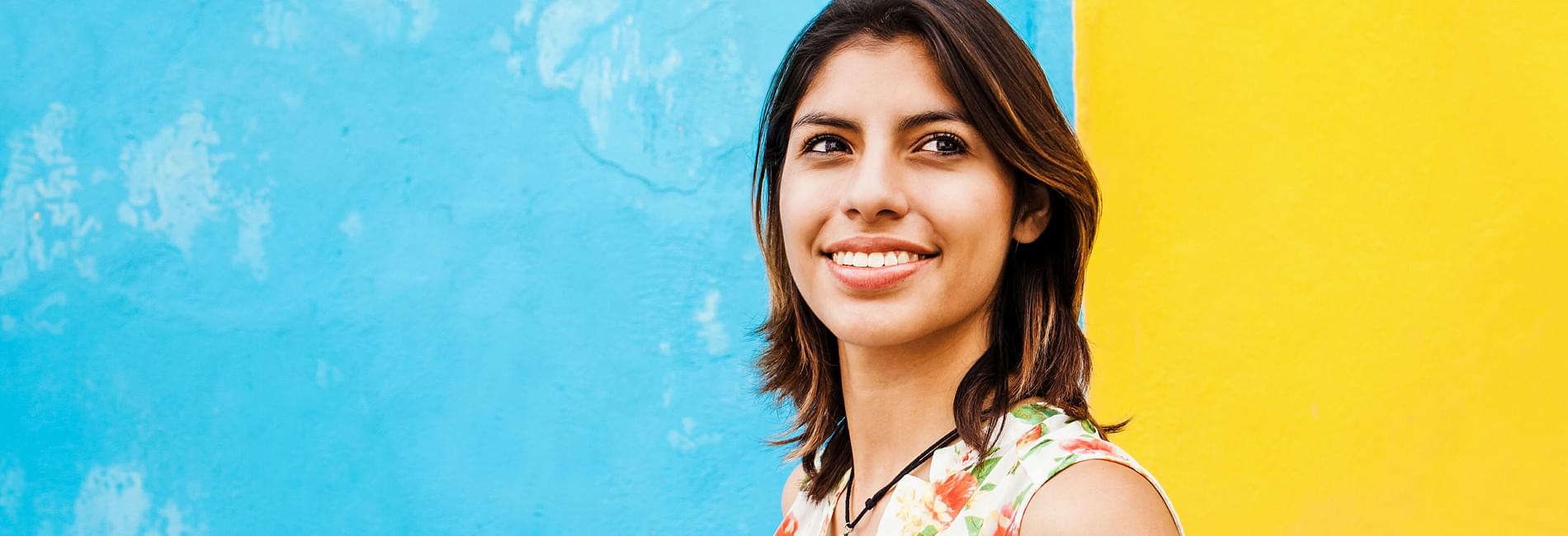  Woman smiling in front of artistic wall. 