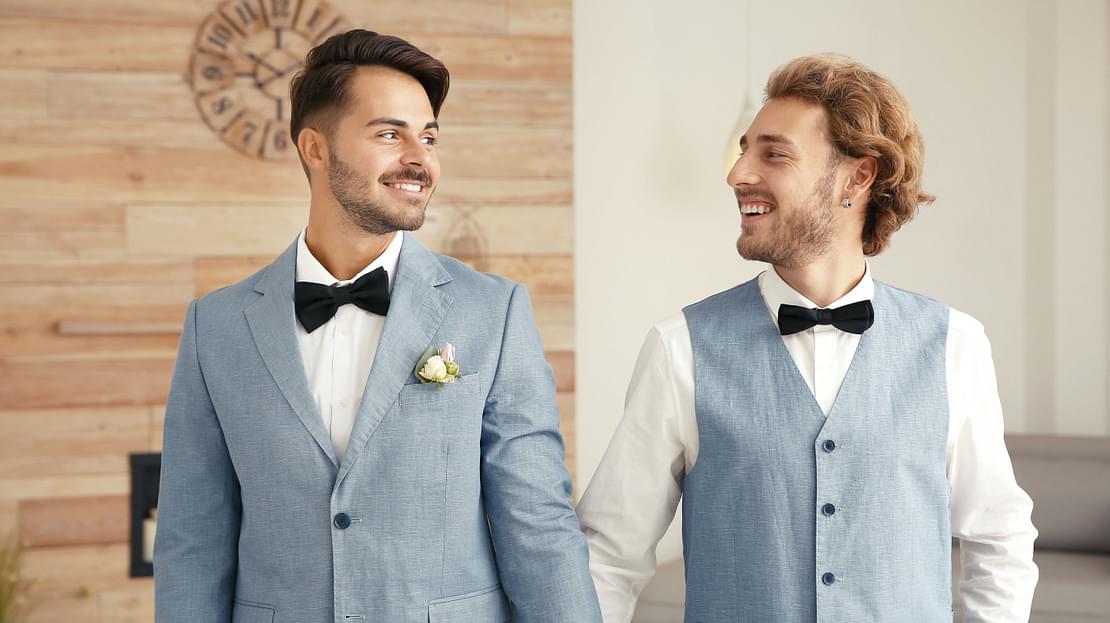 Same-sex couple smiling and holding hands at their wedding