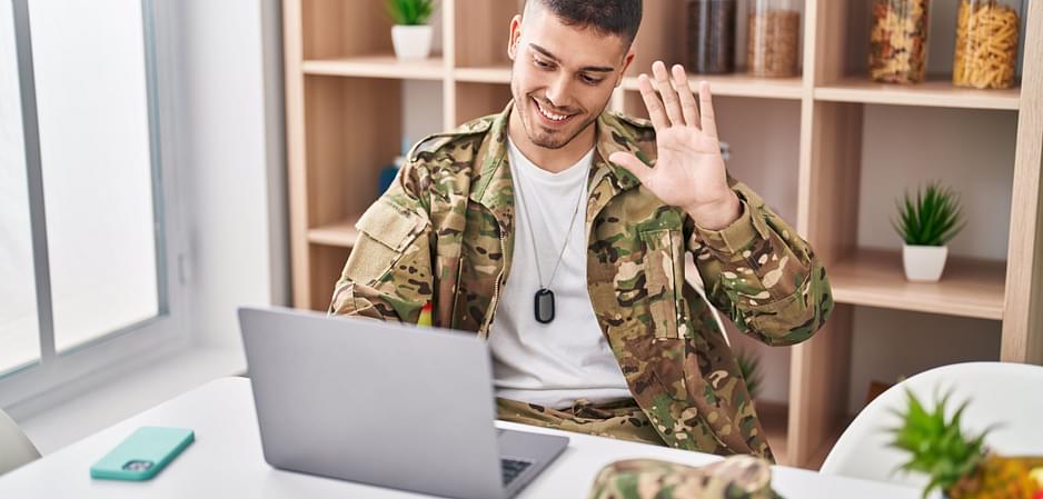 Military man waves to his partner over video call