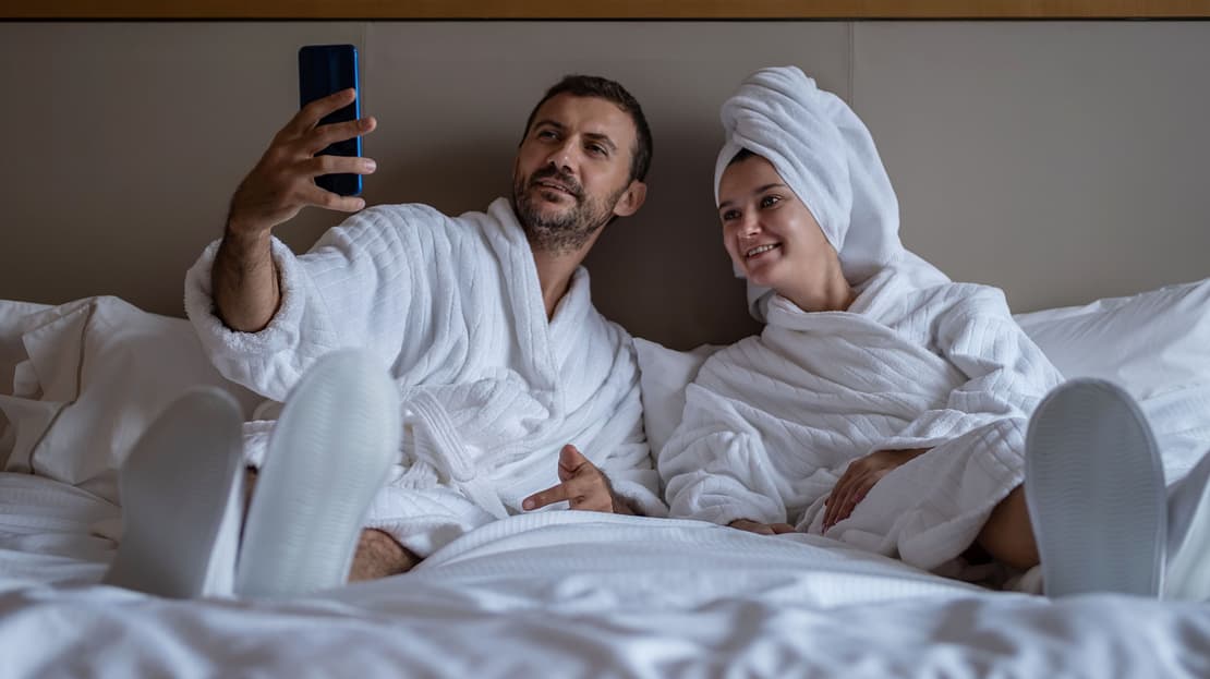  A couple in bath robes looks at a phone 