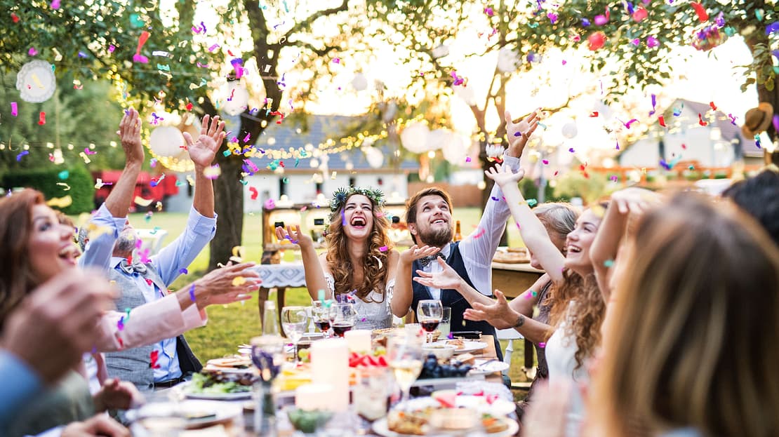  People at a wedding party cheer and throw confetti into the air 