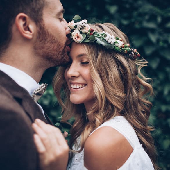 Groom kissing bride on forehead