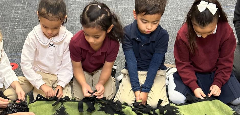 Children tying a fleece blanket